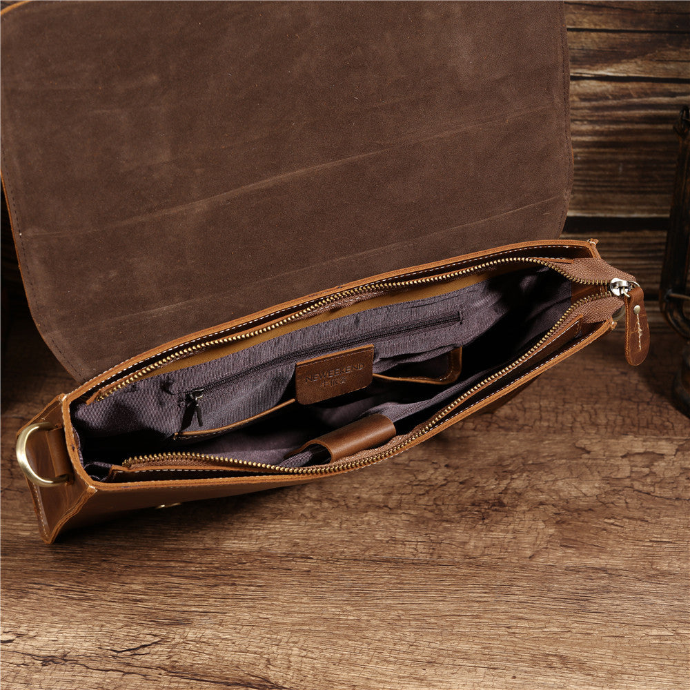 Sac en cuir marron ouvert avec intérieur en tissu gris et poche zippée sur fond bois