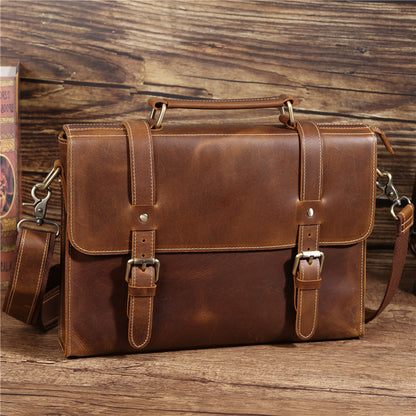 Sacoche homme marron en cuir vintage avec anse et bandoulière sur fond bois