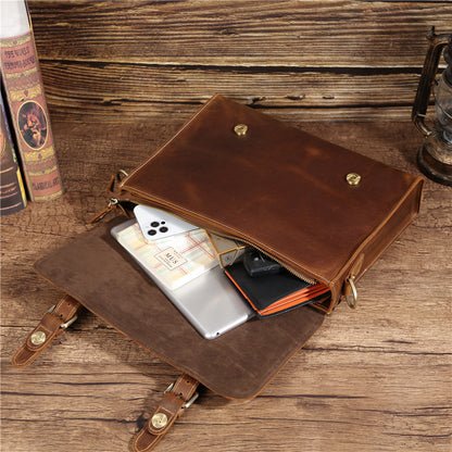 Sac en cuir marron ouvert sur table en bois avec téléphone, carnet, tablette et lunettes